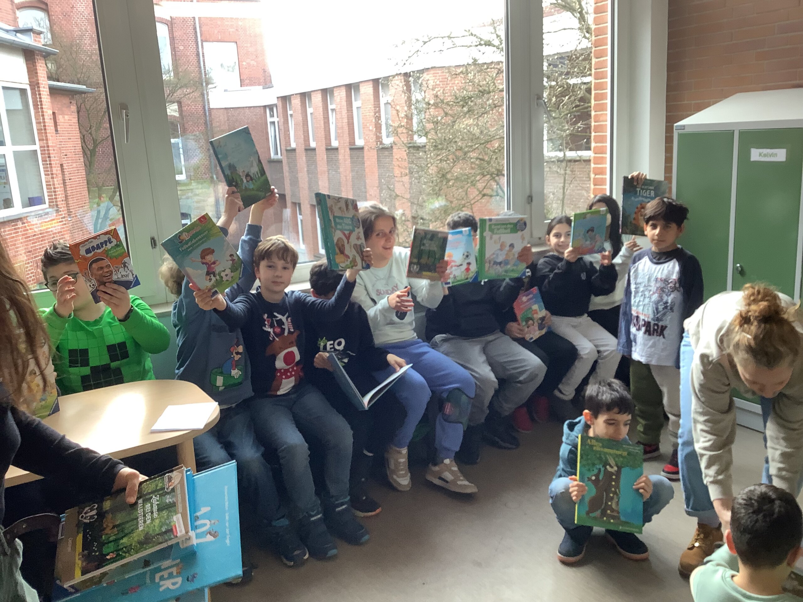 Kinder freuen sich über Bücher und halten sie hoch